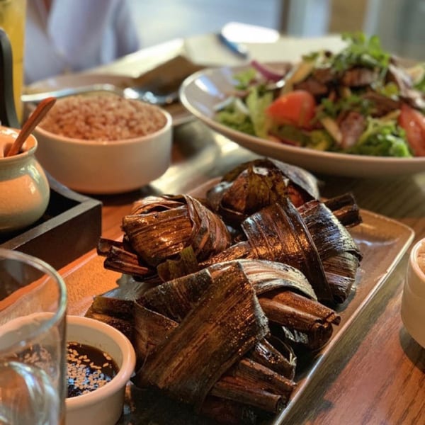 Bai Tong Thai Restaurant's pandan chicken, brown rice, and beef salad on a wooden table.