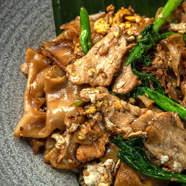 Close-up of Bai Tong Thai Restaurant's Pad See Ew with wide noodles, pork, egg, and Chinese broccoli.