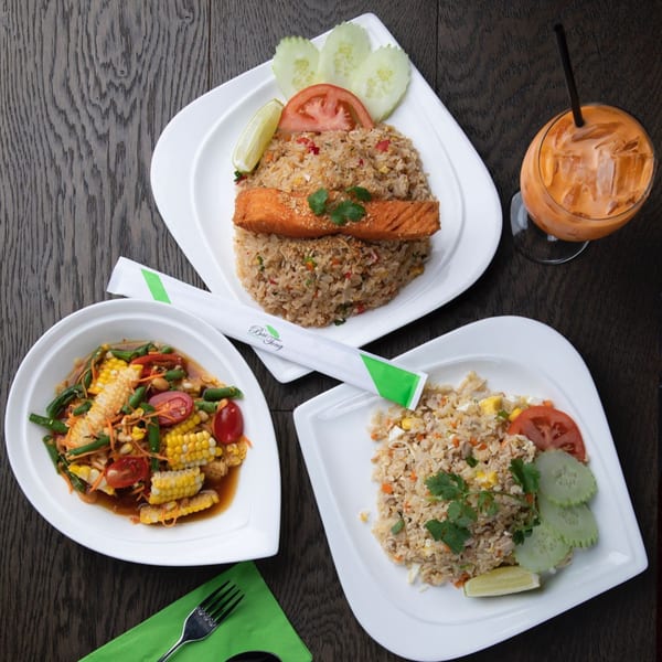 Three Thai dishes: salmon fried rice, corn salad, chicken fried rice, and a Thai iced tea.