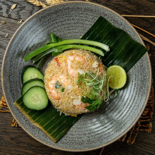 Bai Tong Thai Restaurant's shrimp fried rice, garnished with cucumber, scallions, and lime on a banana leaf.