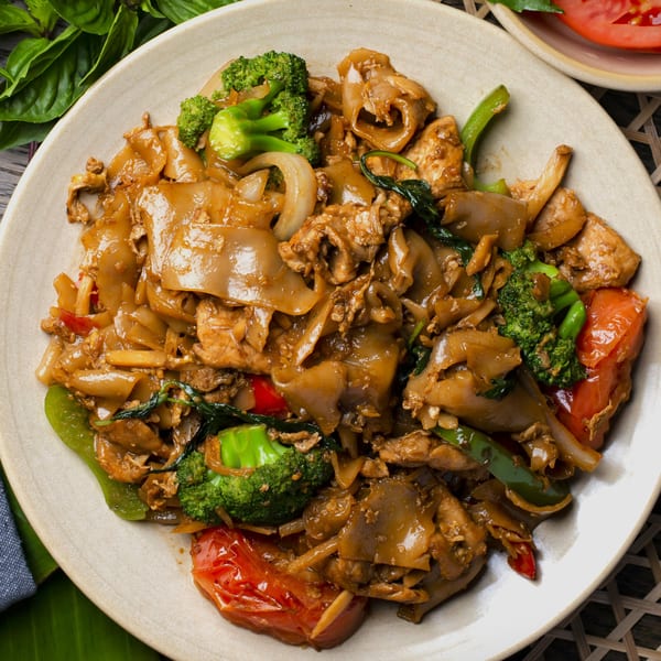 Close-up of Bai Tong Thai's Pad See Ew with wide noodles, chicken, broccoli, and tomatoes.